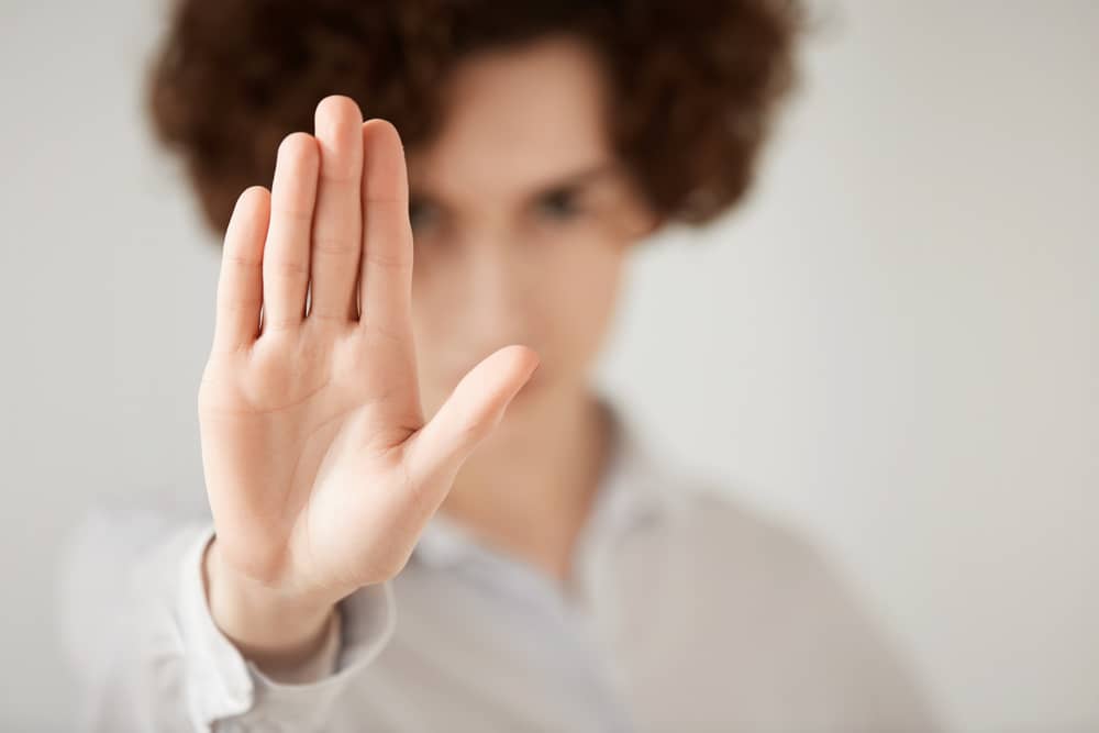 Close up isolated shot of woman with short brunette hair making stop gesture with her hand. Female entrepreneur showing stop sign, not wanting to continue business talks. Selective focus on the hand