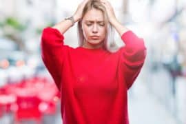 Young blonde woman wearing winter sweater over isolated background suffering from headache desperate and stressed because pain and migraine. Hands on head.
